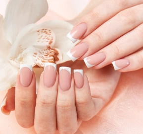 Woman showing French manicure holding white orchid pink background